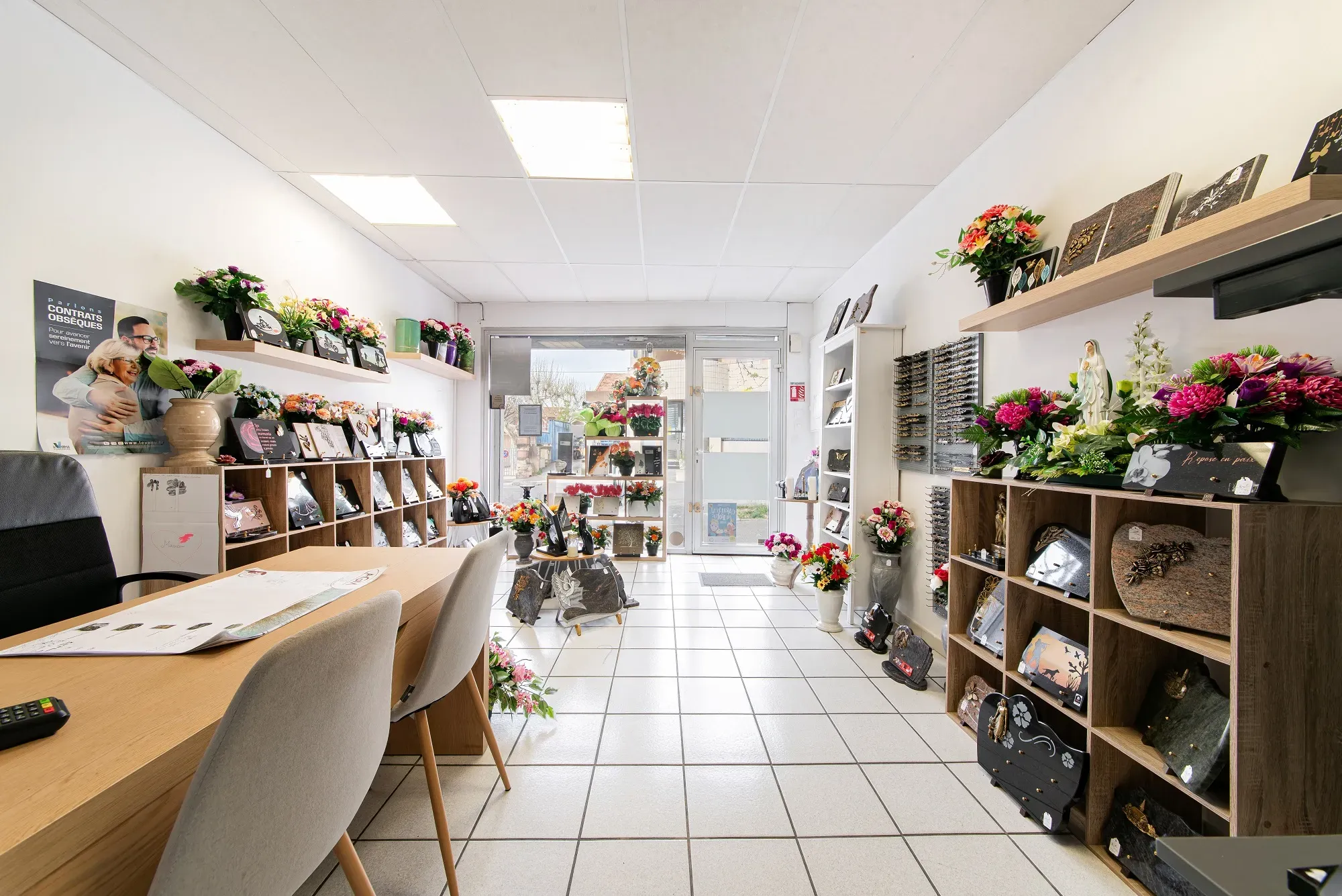 Intérieur d'un magasin de pompes funèbres avec plaques et fleurs.