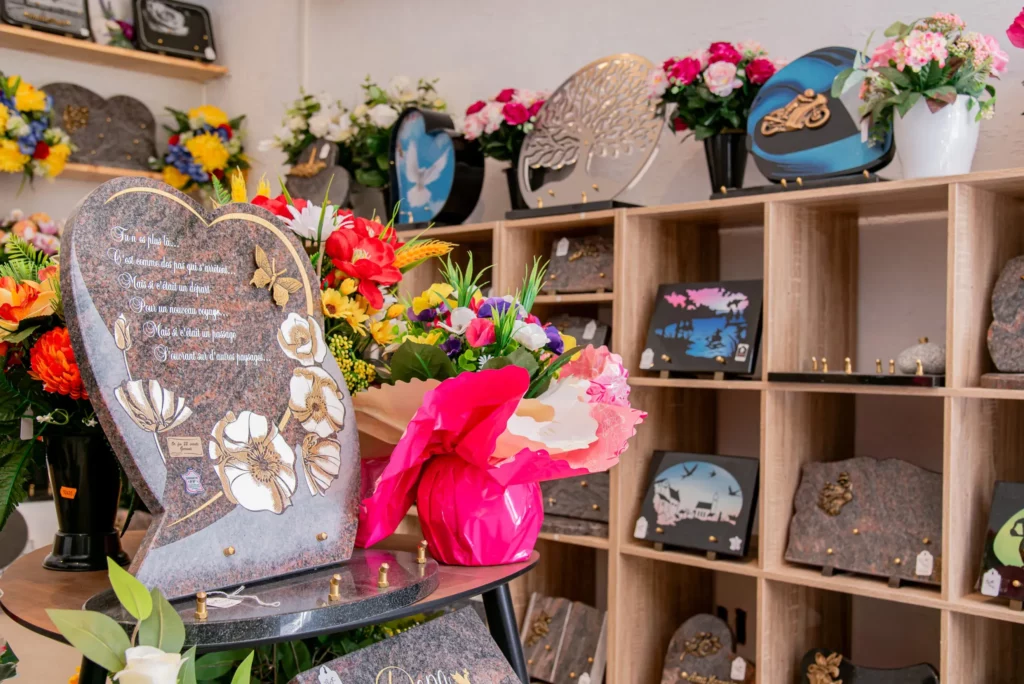 Boutique d'articles funéraires avec plaques gravées et fleurs.