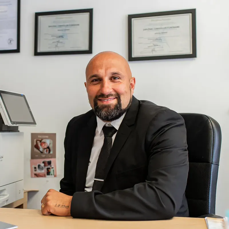 Directeur d'agence en costume noir souriant à son bureau.